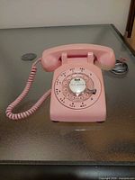 Front view of pink Bell rotary telephone showing dial and handset
