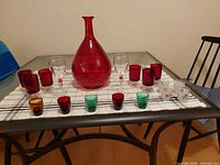 All items together on table showing decanter, tumblers, wine glasses, coloured and printed shot glasses