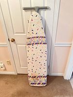 Ironing board standing upright showing full cover pattern and T-shaped top handle