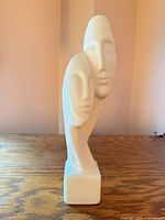 Front view of white ceramic abstract double-face sculpture on wood surface