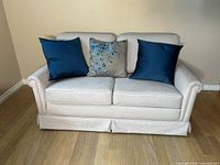 Front view of beige microfiber loveseat with three pillows