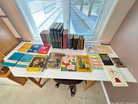Full table view showing approximately 35 vintage books including reference set and assorted children’s titles