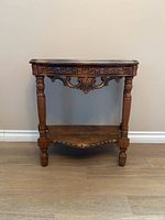 Front view of the accent table showing carved apron, turned legs, lower shelf