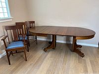 Dining table with three chairs against wall, leaves inserted