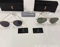 Both sunglasses with boxes, cloth and cards