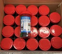 Cardboard carton filled with red-lidded containers, one label visible showing product
