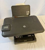 Top and front view showing overall printer, control panel, trays, HP logo, cosmetic wear