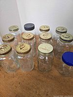 Group of 12 clear embossed mason jars with various lids