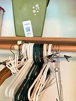 Cluster of assorted hangers on rod below small green bin