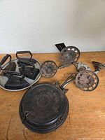 Group view of cast iron waffle maker, four irons on metal tray, metal wall sconce