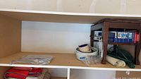 Shelf showing gel packs bag, stacked bowls, wood footstool, extension cord, Blue Ice box