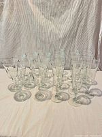Front view of 20 clear stemmed glasses showing knobby stems and mix of bowl shapes
