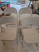 Front view of four beige metal folding chairs