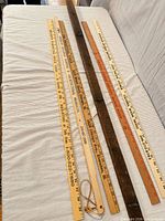Five long pieces laid side-by-side on sofa showing yardsticks, wood hook rail and metal strip