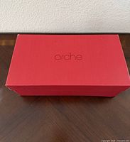 Closed red Arche shoe box on table