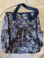 Front view showing paisley pattern, front and side pockets, top handles