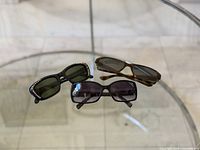 All three pairs of sunglasses on glass tabletop