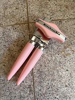 Front view of pink KitchenAid manual can opener showing full handles and cutting head