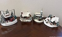 Full set of four Thomas Kinkade lighted village sculptures on table