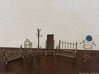 All six brass miniature furniture pieces lined up on surface