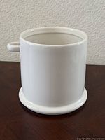 front view of white ceramic utensil holder showing loop handle and base