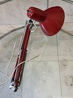 Folded red metal architect lamp showing arm, tension springs, wiring