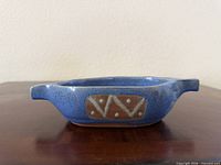 Side view showing blue glaze, tan geometric panel, both handles