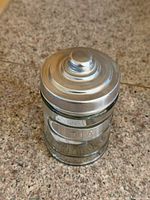 Front view of clear glass tea canister with metal lid