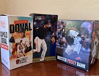Three boxed items: Camilo Doval bobblehead, Brandon Crawford bobblehead, Buster Posey bank