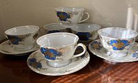 Six porcelain teacups and six saucers arranged on tabletop