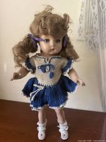 Full view of doll standing on surface in crocheted outfit and shoes