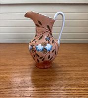 Front view of peach ceramic pitcher with blue flower design