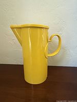 Left side view of yellow melamine pitcher showing handle and lid