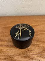 Lidded round black enamel box with gold bamboo design
