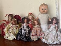 Group shot of all eight dolls on wooden surface