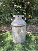 Full view of galvanized milk can showing lid, handles and embossed text