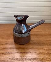 Front view showing brown glaze, grey band, side handle, fluted spout