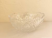 Angled view of the heavy clear pressed glass bowl showing starburst base and scalloped sawtooth rim