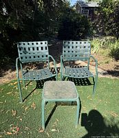 two green strap chairs with one square side table outdoors