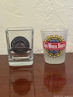 Square clear shot glass with metal medallion and frosted shot glass with printed railroad logo