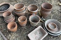 Overview of assorted terracotta pots, saucers and tray lying on ground