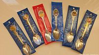 Front view of six packaged souvenir spoons