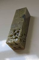 Angled view showing carved dragon motif on top and overall stone texture
