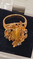 Front view of ring showing central cat’s eye stone and rhinestone accents
