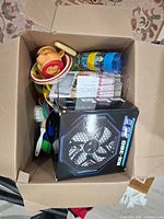 Items packed in box showing children’s dishes and boxed computer fan