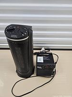 Front view of ceramic tower heater and Gymax box heater showing controls and cords