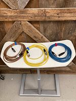 Overview of three coiled XLR cables in brown, yellow and blue on table