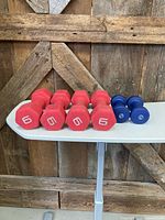 six dumbbells on table: four red 6-lb and two blue 3-lb