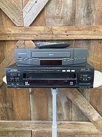 Front view of Magnavox VCR stacked on Apex DVD player with remote on top