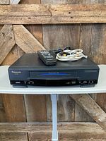 Front view of Panasonic PV-4601-K VCR with remote and RCA cables on top
